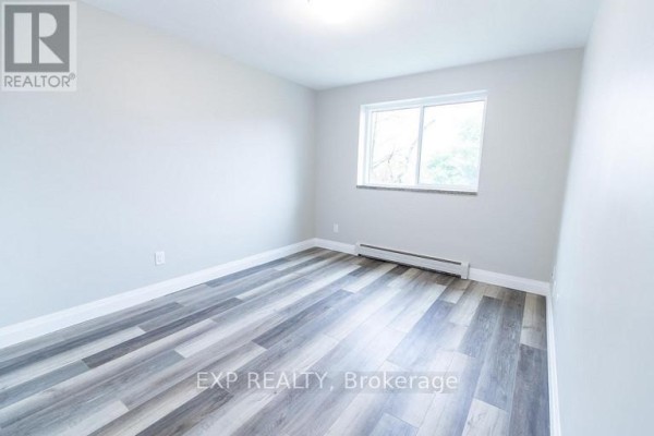 Empty bedroom with light grey walls, white trim, and wood-look laminate flooring. - 3 - 3815 Portage Road, Niagara Falls