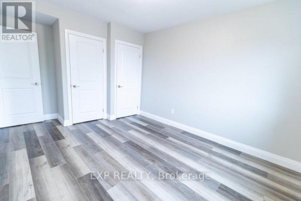 Empty room with light grey walls, white doors, and wood-look laminate flooring. - 3 - 3815 Portage Road, Niagara Falls
