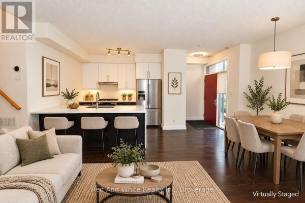 Open concept dining area and kitchen with white countertops, stainless steel appliances, and dark wood floors. - 3 - 4080 Parkside Village Drive, Mississauga