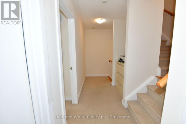 Modern kitchen with white cabinets, black base cabinets, stainless steel refrigerator, and an island with a sink. - 3 - 4080 Parkside Village Drive, Mississauga