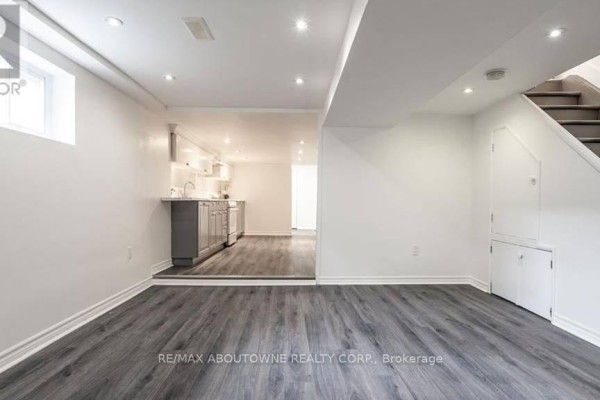 Living area with grey wood-look flooring, looking into an open doorway to a kitchen. - 3 - 43 Crooks Street, Hamilton
