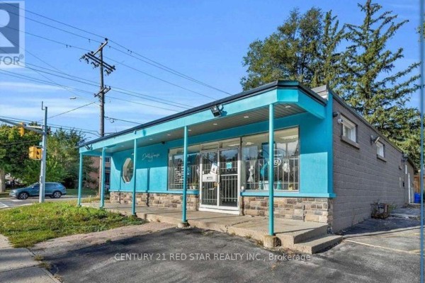 Front view of a commercial building with a turquoise facade, stone base, and large windows. - 3 - 44 Centre Street N, Brampton