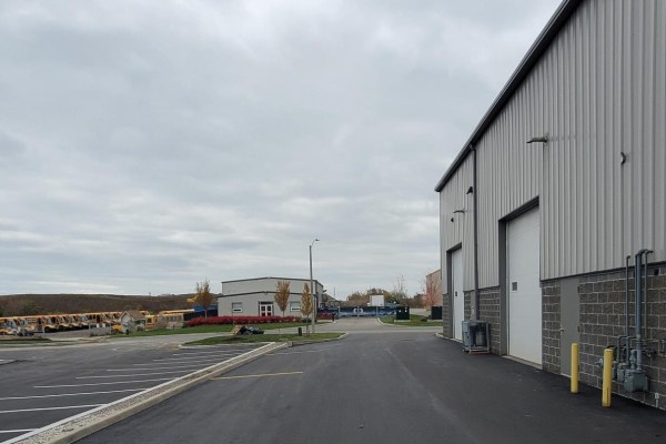 View down a paved driveway towards other buildings and a lot filled with school buses. - 3 - 44 Ditton Drive, Hamilton