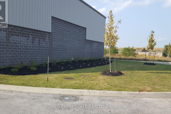 Landscaping with grass, mulch, and young trees along the side of a commercial building. - 3 - 44 Ditton Drive, Hamilton