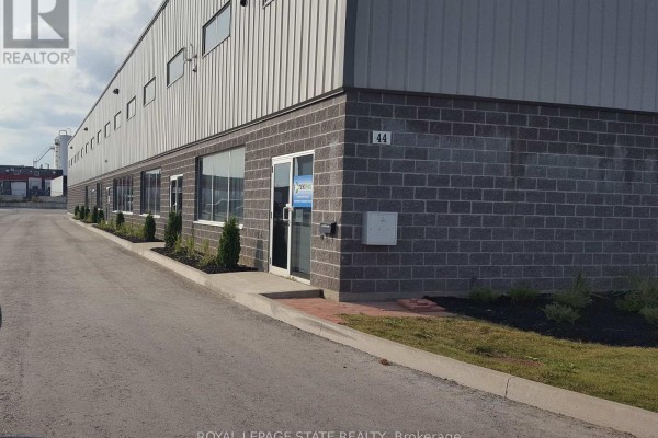 Side view of a commercial building with gray brick facade and a glass door entrance. - 3 - 44 Ditton Drive, Hamilton