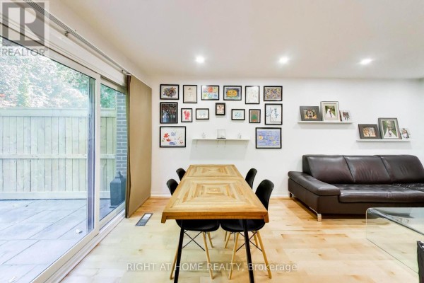 Dining area with wooden table, black chairs, and sliding glass doors opening to a patio. - 3 - 46 Three Valleys Drive, Toronto