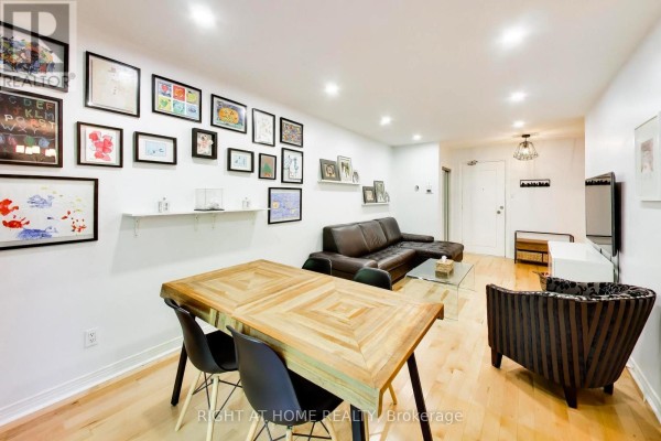Living and dining area with wooden table, black chairs, brown leather sofa, and gallery wall. - 3 - 46 Three Valleys Drive, Toronto