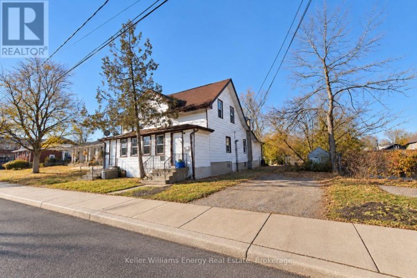 Side view of the white duplex showcasing its structure and surrounding trees. - 3 - 5 Crandall Street, Kawartha Lakes