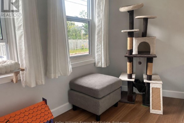 Corner with a grey ottoman, cat tree, and windows overlooking the backyard. - 3 - 5 Crandall Street, Kawartha Lakes