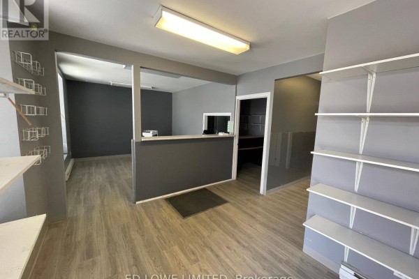 Interior view of a commercial space with grey walls, grey reception counter, and white shelves. - 3 - 511 Welham Road, Barrie
