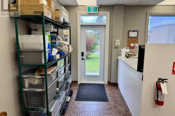 Interior hallway with shelving units filled with supplies, a door leading outside, and a reception counter. - 3 - 5360 Canotek Road, Ottawa