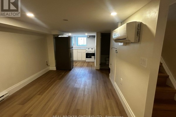 Looking down a narrow hallway with cream-colored walls and a wooden handrail. - 3 - 659 Vaughan Road, Toronto