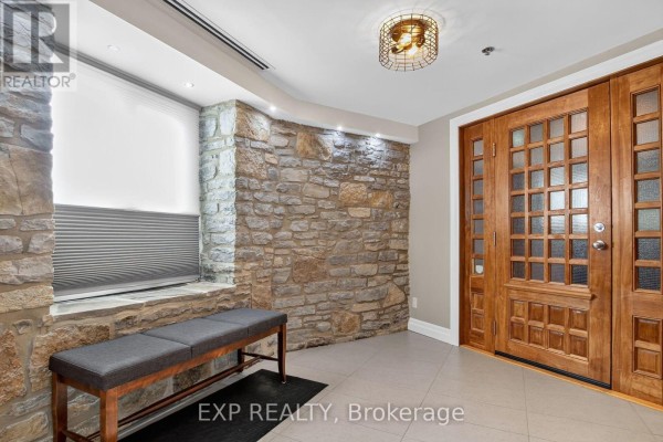 Apartment building interior with stone wall, bench, and double wooden doors. - 3 - 7 Mill Street, Mississippi Mills