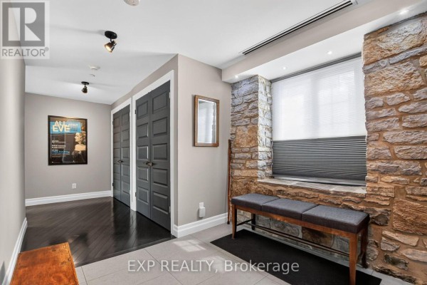 Apartment hallway with dark wood floors, grey doors, and stone accent wall. - 3 - 7 Mill Street, Mississippi Mills