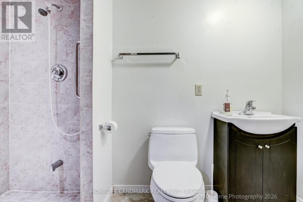 Finished basement with laundry machines, a desk with a monitor, and a door to a bathroom. - 3 - 736 Kingston Road, Toronto