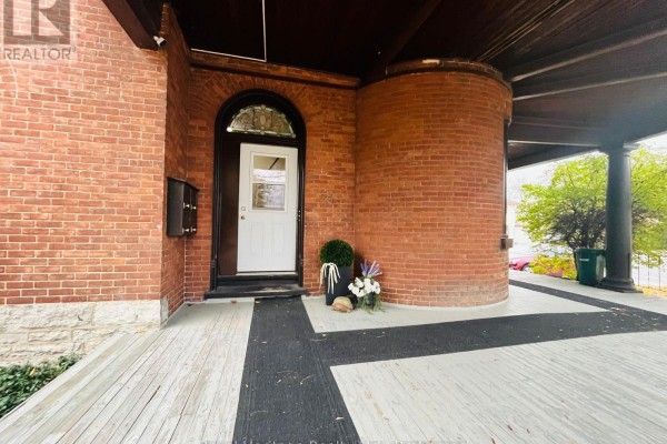 Covered porch with brick pillars, arched doorway, and white door. - 3 - 80 Bridge Street W, Belleville