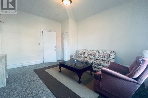 Living room featuring a sofa, armchair, coffee table, and light-colored walls. - 3 - 80 Bridge Street W, Belleville
