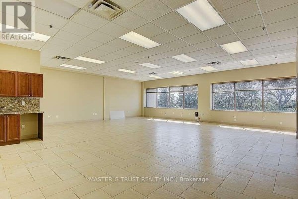Empty commercial space with beige walls, tan tiled floor, and kitchenette. - 3 - 8111 Jane Street, Vaughan