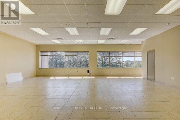 Spacious commercial interior with beige walls, tan tiled floor, and large windows. - 3 - 8111 Jane Street, Vaughan