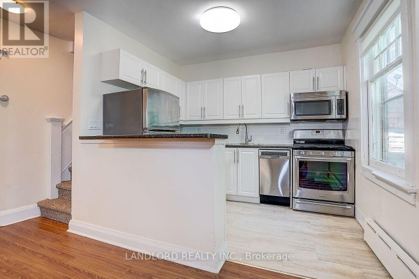 White kitchen with granite counters, stainless steel appliances, and breakfast bar. - 3 - 92 Neville Park Boulevard, Toronto
