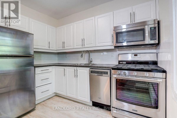 U-shaped white kitchen with white subway tile backsplash and stainless appliances. - 3 - 92 Neville Park Boulevard, Toronto