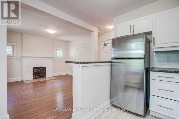 View from the kitchen showing a living room with a fireplace and doorway. - 3 - 92 Neville Park Boulevard, Toronto