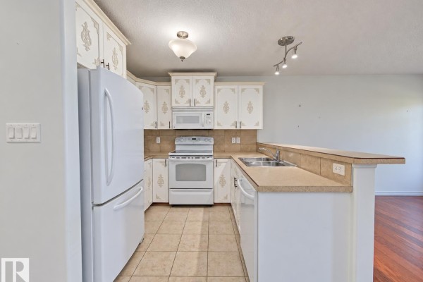 View of the kitchen area with white cabinetry and stainless steel appliances. - #3 10 Woodcrest Ln, Fort Saskatchewan