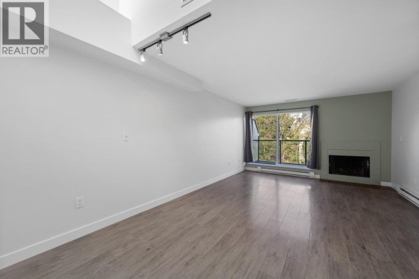 Spacious living room with large windows, fireplace, and track lighting. - 3 1355 W 4th Avenue, Vancouver