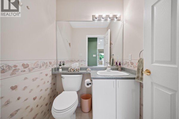 Powder room with a toilet, vanity with sink, and seashell-patterned wallpaper. - 3 1370 Riverwood Gate, Port Coquitlam