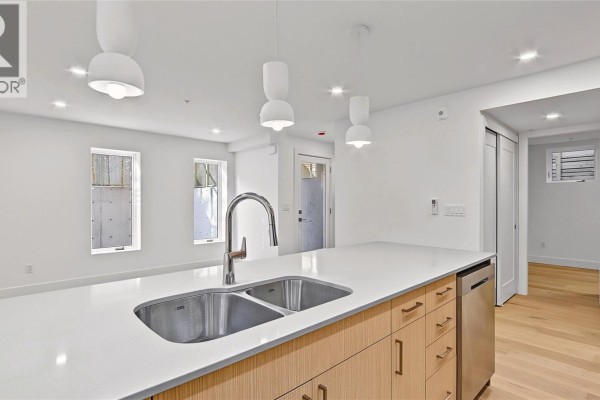 Close-up of kitchen island with double sink, chrome faucet, and light wood cabinetry. - 3 1721 Adanac St, Victoria