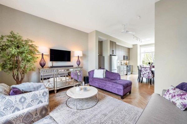 Living room and open-concept kitchen with grey cabinets, stainless steel appliances, and a dining table. - 3 17555 57a Avenue, Surrey