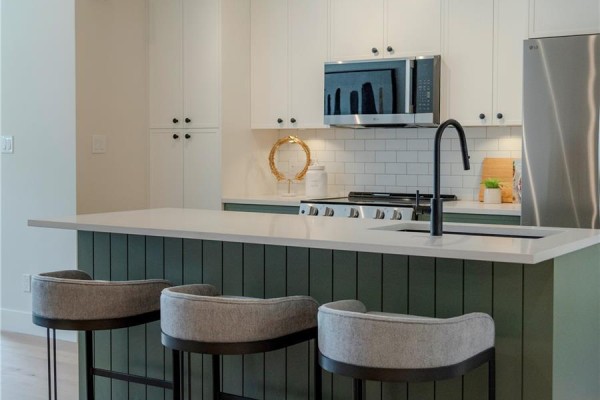 Kitchen with stainless steel appliances, island, and dining area with table and chairs by the window. - 3 1830 Allenby St, Saanich