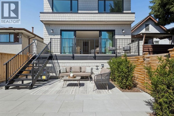 Backyard patio with outdoor furniture, stairs leading up to a balcony, and wooden fence. - 3 2124 E 8 Avenue, Vancouver