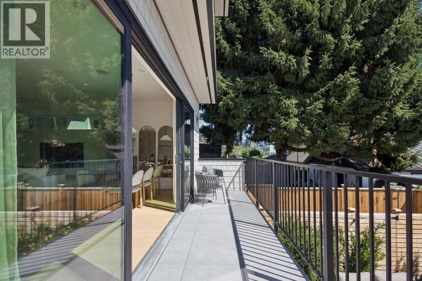 View from balcony looking towards the backyard, showing trees and a portion of the house exterior. - 3 2124 E 8 Avenue, Vancouver