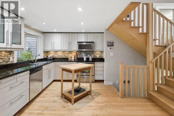 View of the kitchen and a wooden staircase leading upwards. - 3 230 W 15th Street, North Vancouver