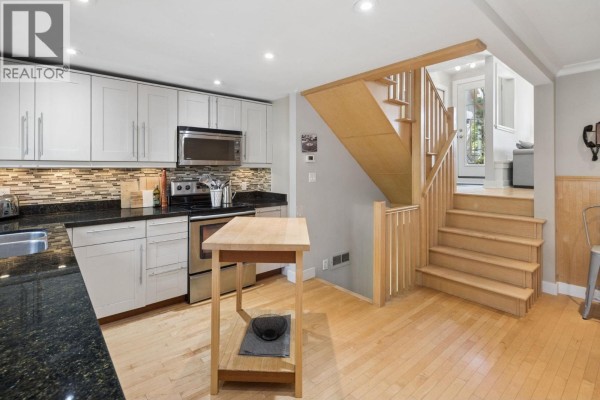 Kitchen and dining area with a built-in bench seat and light wood flooring. - 3 230 W 15th Street, North Vancouver