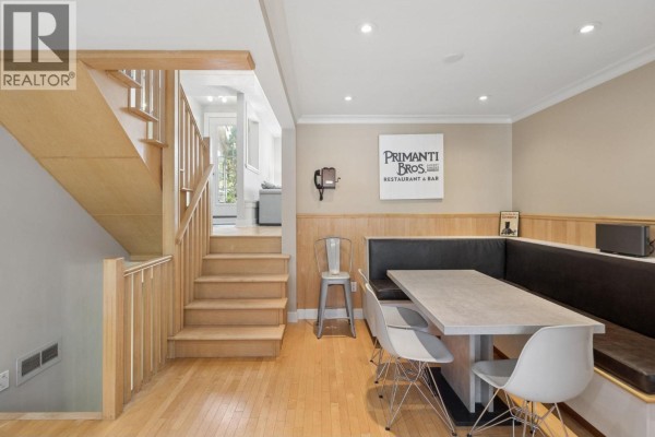 Dining area with a large built-in booth, metal chairs, and a wooden staircase. - 3 230 W 15th Street, North Vancouver
