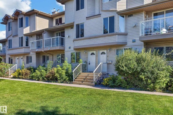 Front exterior of a beige townhouse complex with two identical entrances and stairs. - #3 2505 42 St Nw, Edmonton
