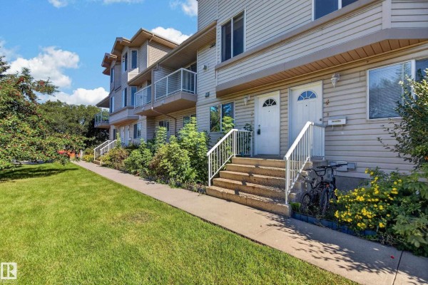 Close-up of two townhouse entrances with stairs, landscaping, and a bicycle. - #3 2505 42 St Nw, Edmonton