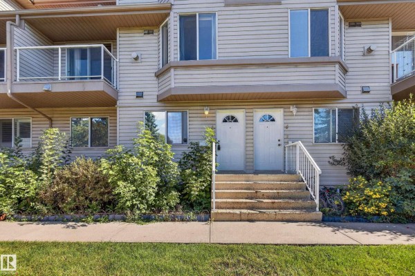 Front view of two beige townhouse doors with stairs and surrounding greenery. - #3 2505 42 St Nw, Edmonton