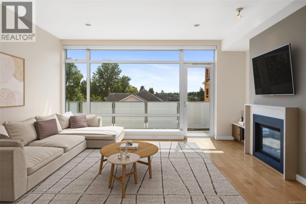 Living room with sectional sofa, fireplace, and large window overlooking neighborhood. - 3 2830 Irma St, Victoria