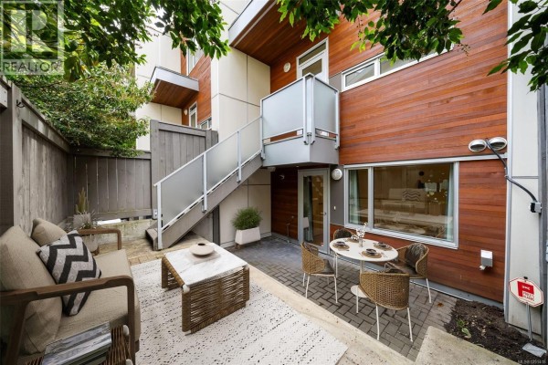 Patio area with seating, coffee table, and exterior stairs on townhouse. - 3 2830 Irma St, Victoria