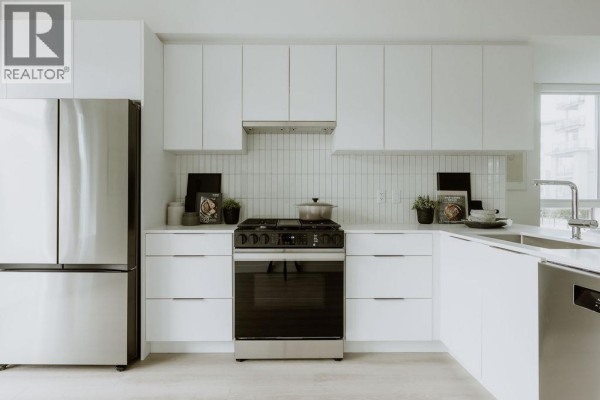 Modern kitchen with white cabinets, tiled backsplash, and stainless steel appliances. - 3 4552 Cattail Way, Tsawwassen