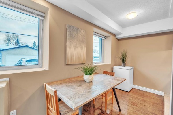 Living room with hardwood floors, two chairs, and modern artwork on the wall - 3 620 Jefferson Avenue, Winnipeg