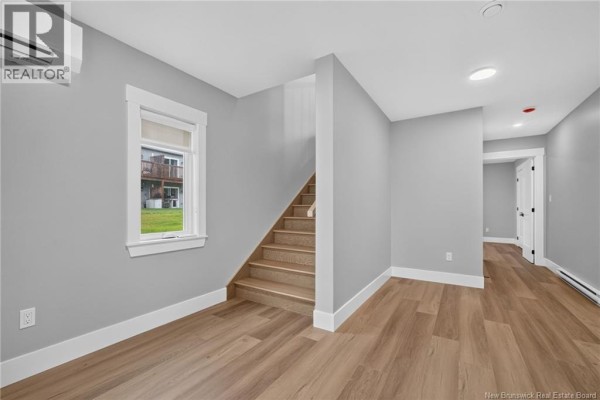 Interior hallway with grey walls, light wood flooring, a window, and a staircase leading upstairs. - 3 Avenue Denis, Saint Antoine