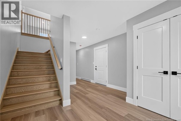 Interior hallway with light wood flooring, a wooden staircase with black railings, and white doors. - 3 Avenue Denis, Saint Antoine