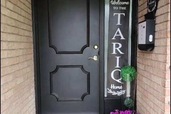 Close-up of a black front door with decorative panels and a vertical welcome sign. - 3 Blackthorn Lane E, Brampton