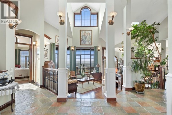 Interior foyer with a stone tile floor, wooden banisters, high ceilings, and large windows with a view. - 3 Blackwell Bay, Rural Rocky View County