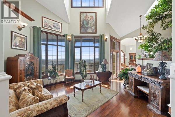 Living room with hardwood floors, a couch, coffee table, large windows, and antique furniture. - 3 Blackwell Bay, Rural Rocky View County