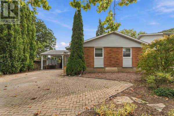 Front view of a brick house with a covered carport and mature trees. - 3 Brian Avenue, St  Catharines